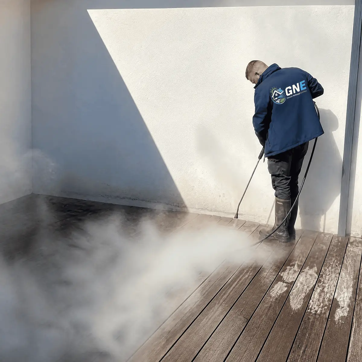 Technicien GNE nettoyant un sol extérieur à la vapeur